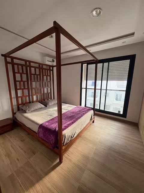 Chambre avec lit à baldaquin en bois sombre et cloison vitrée