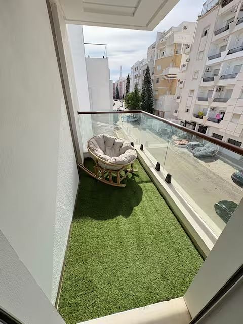 Le balcon habillé de gazon synthétique, ouvert sur la rue