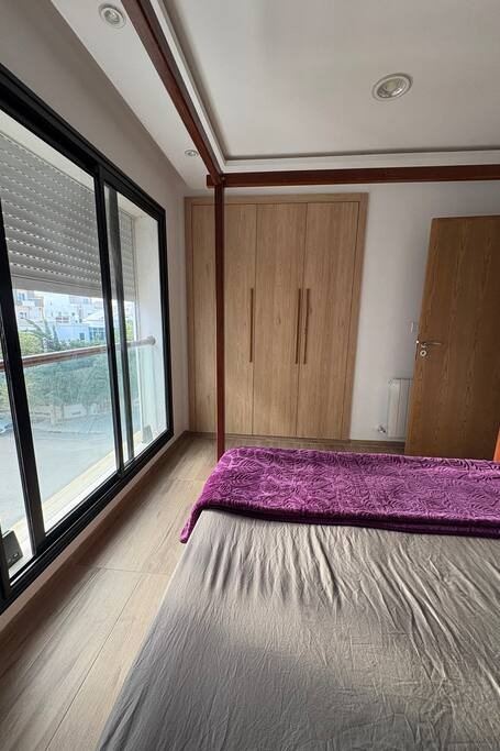 La chambre côté fenêtre, couvre-lit fuchsia et grande baie