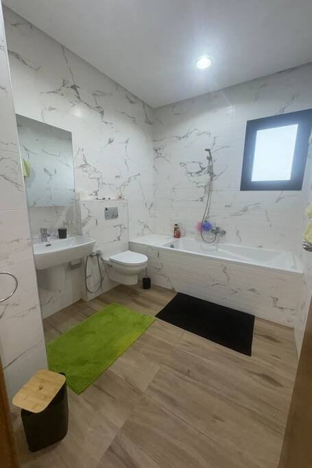 La salle de bain côté baignoire, WC et petite fenêtre