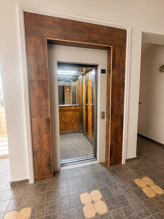 Palier privatif du cinquième et porte d'ascenseur encadrée de bois précieux