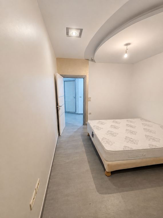 Seconde chambre, mur d'enduit sablé et lit face à la fenêtre