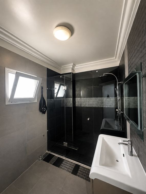 Salle de douche du couloir : grès sombre, douche à l'italienne et paroi de verre