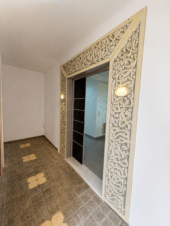 Portique d'entrée en bois ajouré et calligraphié, ouvrant sur la galerie